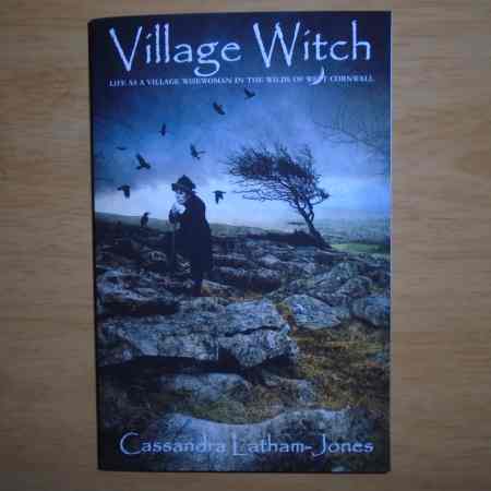 A copy of book, Village Witch by Cassandra Latham-Jones, published by mandrake of oxford. Cover shows artwork by Angie Latham