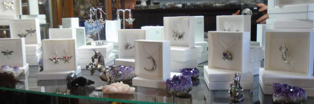 cornish pewter jewelry in white gift boxes featuring owls, mermaids moons and cats with cornish pewter figurins of dragons and unicorns interspersed with small pieces of amethyst crystal