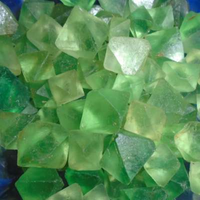 a close up view of a dish of octohedral fluorite, a gemstone with 8 sides in a pale green colour